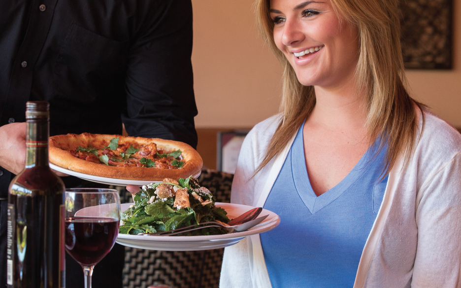 Lady being served pizza and salad